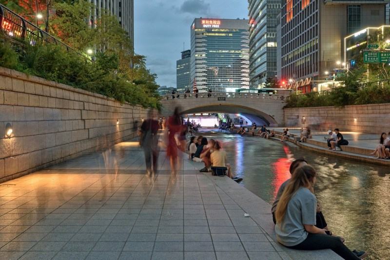 Pessoas na margem do riacho urbanizado de Cheonggyecheon, em Seul, capital da Coreia do Sul. Desde sua inaugurao, em 2005, o local se tornou popular entre os residentes e turistas.